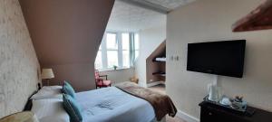 sypialnia z łóżkiem i telewizorem z płaskim ekranem w obiekcie Victoria Hotel w mieście Portknockie