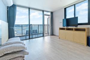 ein Wohnzimmer mit einem Flachbild-TV und großen Fenstern in der Unterkunft Gold Beach Resort in Yeosu