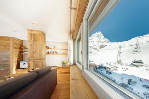 a living room with a couch and a large window at HelloChalet - Maison Rêve Blanc - Ski to door with Matterhorn view in Breuil-Cervinia