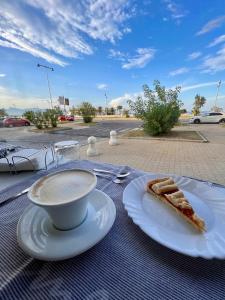 een tafel met een bord taart en een kopje koffie bij Agathè Luxury Bed and Breakfast in Marina di Schiavonea