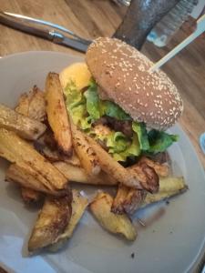 un sándwich y papas fritas en un plato blanco en Grande chambre d'hôte avec piscine chauffée et Jacuzzi à disposition, en Chef-Boutonne