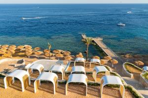 eine Gruppe von Stühlen, einem Tisch und dem Meer in der Unterkunft Meraki Resort Sharm El Sheikh Adults only in Sharm El Sheikh