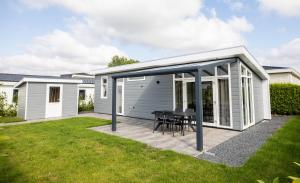 an extension of a house with a patio with a table at Rhederlaagse Meren in Lathum