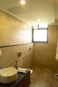 a bathroom with a sink and a toilet and a window at Chang's Garden & Resort in Golāghāt