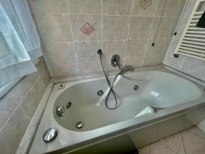 a white bath tub in a tiled bathroom at Casa Conchiglia in Vado Ligure +3 photos