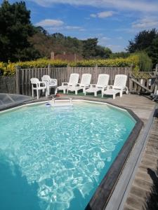 una piscina con sillas blancas y una mesa en Gite Atypique Caravane Vintage et piscine ouverte du 15 Mai au 30 Septembre en Godinne
