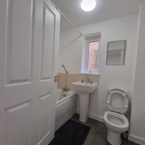 a white bathroom with a toilet and a sink at Modern home with Netflix, NowTV & 2private parking in East Tilbury