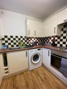 a kitchen with a washing machine and a sink at Spacious 3 bed flat a stones throw from the beach in Pakefield