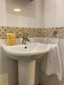 a white sink in a bathroom with a towel at Spacious 3 bed flat a stones throw from the beach in Pakefield