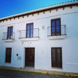 un edificio blanco con 2 entradas y 2 balcones en La Casona de la Sierra, en Higuera de la Sierra