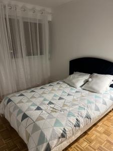 ein Bett in einem Schlafzimmer mit einem großen Fenster in der Unterkunft Spacieux et confortable appartement en résidence in Pontoise