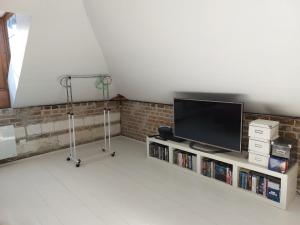 a living room with a television on a shelf with books at Maison au pied de la cathédrale Amiens centre in Amiens