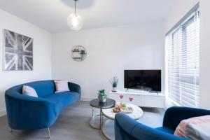 uma sala de estar com sofás azuis e uma televisão em Elliot Oliver - Cosy 2 Bedroom Town Centre Apartment em Cheltenham