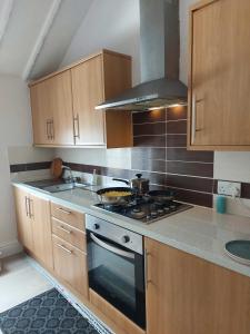 a kitchen with wooden cabinets and a stove top oven at Lovely 2 bedroomed flat in the centre of Longton in Longton