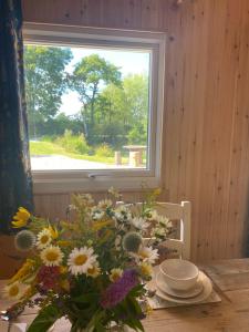 un jarrón de flores sentado en una mesa con una ventana en Kingfisher Cabin - Wild Escapes Wrenbury off grid glamping - ages 12 and over, en Baddiley
