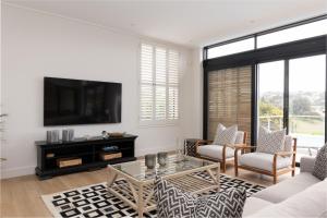 a living room with a tv on a wall at Sunset Villa - brand new home 200m from the beach - top floor only in Plettenberg Bay