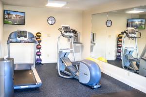 a gym with treadmills and elliptical machines and clocks at Days Inn by Wyndham Champaign/Urbana in Champaign