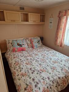 a small bedroom with a bed with flowers on it at Corner pitch 4 berth caravan in Ingoldmells