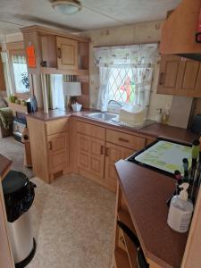 a small kitchen with wooden cabinets and a sink at Corner pitch 4 berth caravan in Ingoldmells