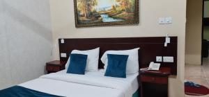 Sadaf Hotel Apartments في صحار: سرير مع وسائد زرقاء وصورة على الحائط