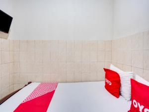 1 dormitorio con 1 cama con almohadas rojas y blancas en OYO Life 91511 Ampel Residence Syariah, en Surabaya