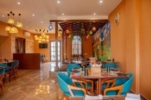 a restaurant with orange walls and blue chairs and tables at The Village Resort Mundra in Mundra