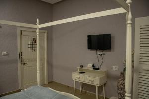 1 dormitorio con 1 cama y TV en la pared en The Village Resort Mundra en Mundra