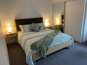 een slaapkamer met een bed met 2 lampen en een spiegel bij Walnut House - Hargreaves St close to Lake Weeroona in Bendigo