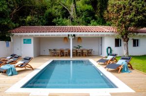 een zwembad met stoelen en een tafel en een huis bij Exclusiva Villa con piscina al borde del mar con vistas de película in Pechón
