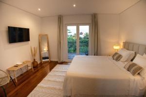 a bedroom with a large white bed and a window at Moinho das Feteiras in Feteiras