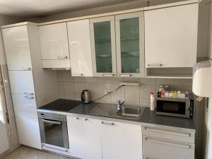 kuchnia z białymi szafkami, zlewem i kuchenką mikrofalową w obiekcie Bus Station Hostel w Prisztinie
