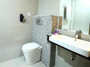 a bathroom with a sink and a toilet and a mirror at Hotel Dafam Pekanbaru in Pekanbaru