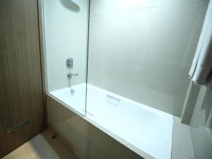 a bathroom with a shower with a glass door at Hotel Dafam Pekanbaru in Pekanbaru