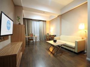 a living room with a couch and a tv at Hotel Dafam Pekanbaru in Pekanbaru