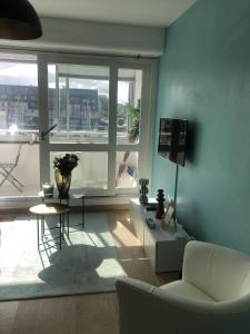 ein Wohnzimmer mit einer weißen Couch und einem großen Fenster in der Unterkunft soleil et bateau in Courseulles-sur-Mer