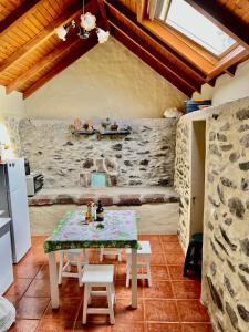 una mesa y sillas en una cocina con una pared de piedra en Cozy Sea View House Fajã da Ovelha, en Calheta