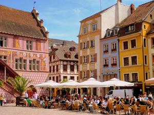 Un groupe de personnes assises à des tables dans une rue avec des bâtiments dans l'établissement Appartement entier rénové dans un écrin de verdure, à Thann