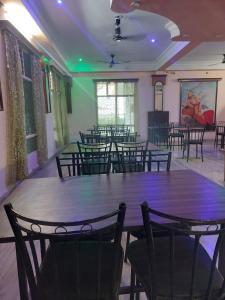 una sala da pranzo con tavoli, sedie e luci verdi di HOTEL SHREE VILLA a Harsola