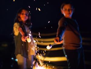 a man and a woman are playing with sparklers at Pura Eco Retreat, Jebel Hafit Desert Park in Al Ain