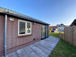 a brick house with a patio in the yard at Op 't Landtweg 35a in Callantsoog
