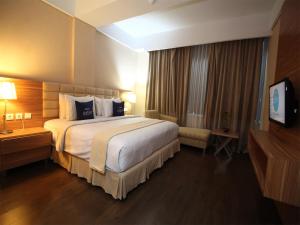 Habitación de hotel con cama grande y TV en Hotel Dafam Pekanbaru, en Pekanbaru