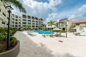 Un complejo con piscina y sillas y un edificio. en Spacious condo with private terrace & Pool, en Palm-Eagle Beach