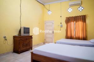 - une chambre avec 2 lits et une télévision sur une table dans l'établissement Wisma Citra Metro Mitra RedDoorz, à Banjarjo