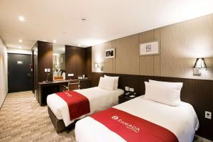 a hotel room with two beds and a desk at Ramada by Wyndham Jeju City Hall in Jeju