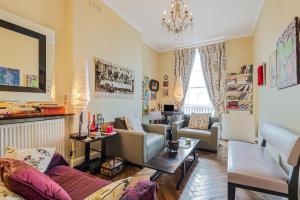 ein Wohnzimmer mit Möbeln und einem Kronleuchter in der Unterkunft Charming one bedroom flat near Maida Vale by UnderTheDoormat in London