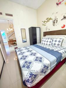 バトゥにあるRumah Kartika Batuのベッドルーム1室(青と白の掛け布団付きのベッド1台付)