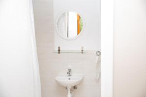 a white bathroom with a sink and a mirror at Mėlynojo karpio barža in Kintai