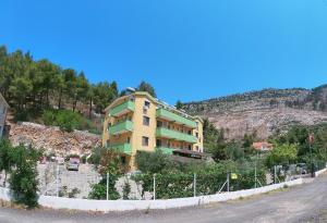 a yellow building on the side of a mountain at Hotel Bolonja in Shëngjin