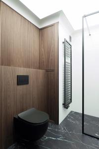 格地尼亞的住宿－Awanport Gdynia M apartments，浴室设有黑色的卫生间和木墙。