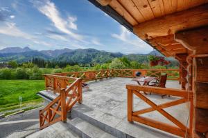 una gran terraza de madera con vistas a las montañas en Willa ANTONÓWKA, en Kościelisko